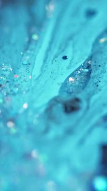 Dikey video. Akrilik boya. Sıvı sim damlası. Odaklanmamış mavi renk parlak metalik pullu parçacıklar mürekkep emülsiyon karışım sıvı akış hareket soyut sanat arka planı.