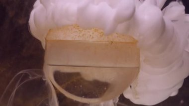 Duman damlası. Mürekkep sıçraması. Odaklanmamış beyaz altın rengi boya, su dumanı, toz bulutu deseni soyut koyu siyah arka planda cam üzerinde yüzüyor..