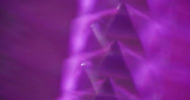 Odaklanamayan ışık üçgenleri. Enerji geometrisi. Sarı, kırmızı, mor, pırıl pırıl, lens, soyut, bulanık arka planda yanıp sönüyor..