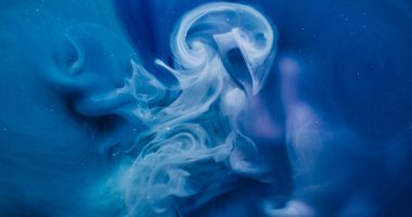 Duman boyası. Akrilik pigment. Soyut sanat arkaplanına yayılan sönük mavi renkli sıvı kimyasal simler ışıl ışıl parlıyor..