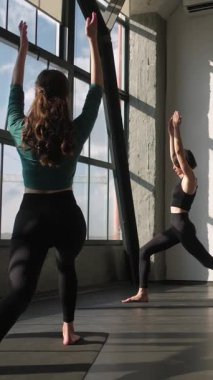 Dikey video. Spor grubu. Yoga eğitimi. Spor salonundaki kadın spor eğitmeniyle egzersiz dengesi kurup pilates dersi vermek için spor salonundaki spor salonundaki paspasa otururlar..