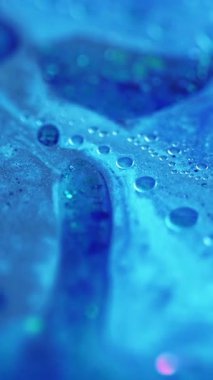 Dikey video. Köpüklü sıvı. Parlak yağ damlası. Odaklanmamış mavi renk parlak tahıl parçacıkları su boyası sıvı pigment emülsiyon hareket soyut sanat arka planı.