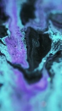 Dikey video. Akışkan sanat. Parıltılı boya döküldü. Odaklanmamış mavi mor renkli parıldayan tahıl tanecikleri akrilik sıvı mürekkep karışımı hareketli soyut arka plan baloncukları.