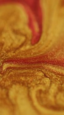 Dikey video. Parıldayan sıvı. Islak mürekkep dokusu. Parlak sıvı dökülmesi. Parlak cila. Odaklanmamış altın rengi parıldayan boya akışı soyut sanat arkaplanı.