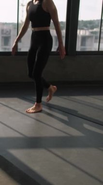 Dikey video. Spor sınıfı. Yoga stüdyosu. Grup üyeleri esneme dersini aşağı doğru eğitiyor. Minder üzerinde köpek Asana ile bayan antrenör spor salonunda poz düzeltmeye yardım ediyor..