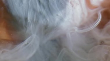 Duman karışımı. Boya yayılıyor. Dekoratif bulanık yüzey gri şeftali rengi sisli su arkaplanının üzerine dökülen beyaz pigment..