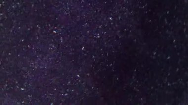 Parıltı etkisi. Bulanık toz parçacıkları. Işıl ışıl parlayan beyaz noktalar. Parlayan toz. Soyut mor arka planda dönen kıvrımlar..