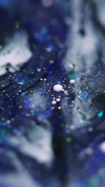 Dikey video. Parlak bir dökülme. Parlak sıvı karışımı. Bulanık mor renkli pırıl pırıl pullu parçacıklar akrilik boya akışkan hareket soyut sanat arka planında Bokeh ışıkları.