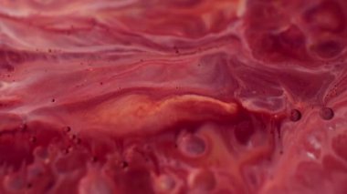 Parlak damlacık. Dalgalanma. Su sıvısında çözünmüş kırmızı beyaz mermer boya ışıl ışıl soyut arkaplan üzerine sıçrıyor.