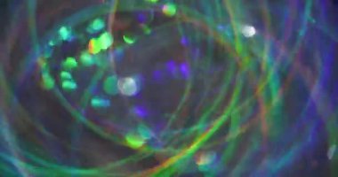 Renkli ışıltı. Bulanık, ışıltılı bir doku. Yeşil mavi turuncu çizgili kaleydoskop yanıp sönen mercek flaşlı arka plan.