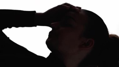 Dikey video. Hüzünlü siluet. Anksiyete stresi. Yalnızlık depresyonu. Koyu renkli karşıtlık profili, boynu uzayan yorgun kadının beyaz boş alanda izole edilmiş yüz hatları..