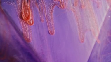 Mürekkep sızıntısı. Işıldayan damlalar. Menekşe mor üçgende kayan turuncu simli damlalar mistik renkli dumanlı su arkaplanı bulanıklaştırır..