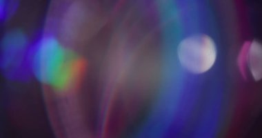 Bulanık renk kıvılcımları. Lens fişeği. Açık mavi mor neon, soyut koyu arkaplan üzerinde bokeh etkisi ile parıldıyor..