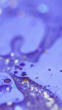 Dikey video. Sıvı boya karışımı. Köpüklü yağ damlası. Odaklanmamış mor renkli parlak parçacıklar akrilik akrilik sıvı mürekkep sızıntısı soyut sanat arka planı ve bokeh ışıkları..