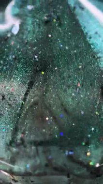 Dikey video. Parlak sıvı damlası. Işıldayan boya. Bulanık yeşil renkli pullu partiküller sıvı ıslak parlatıcı elmas hareketli elmas şekilli soyut sanat arkaplanı ve bokeh ışıkları.