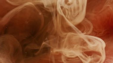 Buhar mürekkebi. Sis boyası. Siyah arkaplanda süzülen sarı turuncu sis örtüsü parçacıkları. Renkli kıvrımlı bulut suyu soyut sihirli bulanık duman.