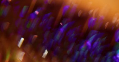 Kristal parlaklık. Görüntü pırıltısı. Mor sarı mavi turuncu bokeh ışık arkaplanını açan çok renkli parçacıklar mercek fişeği.