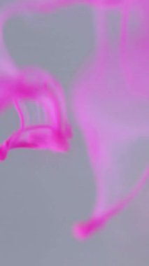 Dikey video. Renk sıvısı. Işıl ışıl parlıyor. Işıl ışıl su. Modern beyaz sanatın soyut arka planında pembe grafik, parlak eğimli düşüş akışı.