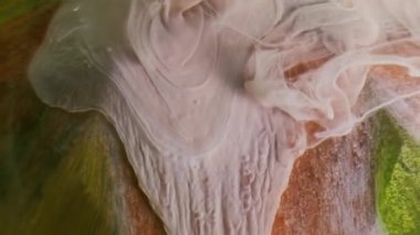 Mürekkep akıyor. Pigment akışı. Renkli sanat sıvısı parıldayan dekoratif yüzeyde karışıyor. Odaklanamayan soyut bej kıvrımlı karışık su arkaplanı.