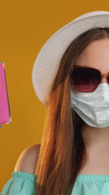 Dikey video. İş ve seyahat. Karantina kısıtlaması. Turist kadın koruyucu maskeli eldiven ve pasaport onaylı oturma izni turuncuyla izole edilmiş..