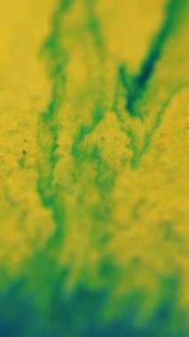 Dikey video. Işıltılı girdaplar düşer. Parlak boya akışı. Odaklanmamış sarı mavi renk parlak parçacıklar desen karışık dalga hareketi soyut sanat arkaplanı.