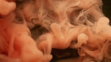 Duman bükme. Boya patlamış. Siyah arka plana yayılmış portakallı puf spreyi. Soyut su rengi lekesi patlaması bulanık fantezi sisi.