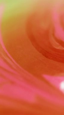 Dikey video. Köpüklü sıvı. Sıvı mürekkep karışımı. Bulanık turuncu pembe renkli parlak toz parçacıkları akrilik boya girdaplı su emülsiyonu hareketli soyut sanat arka planı.