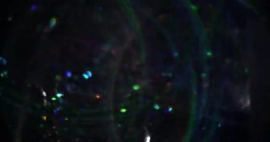 Noel çelengi. Bulanık kıvılcımlar. Lens parçaları koyu siyah bokeh açık sanat arka planında yüzen çok renkli gölgeler.