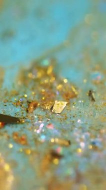 Dikey video. Parıltılı boya karışımı. Işıldayan sıvı doku. Bulanık mavi altın rengi parlak pullu parçacıklar akrilik akışkan mürekkep akışı soyut sanat arka planında Bokeh ışıkları.