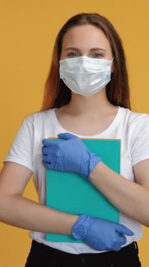 Dikey video. Salgın öğretmen. Karantina eğitimi. Sosyal uzaklık. Korunaklı yüz maskesi eldivenli, kendine güveni tam bir bayan öğrenci..