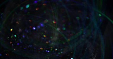 Bulanık çelenk. Parlak arkaplan. Görkemli parlak girdap çok renkli mercek parçacıkları koyu siyah Bokeh ışık efekti üzerinde parlıyor.