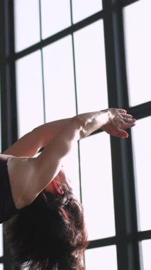Dikey video. Vücut sağlığı. Sabah sporu. Sağlıklı aktivite. Aktif giyimli atletik kadın yoga seansı kas germe jimnastik seti. Spor salonu içinde spor salonu..