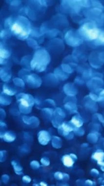 Dikey video. Bokeh ışığı. Mavi işaret fişeği. Işıl ışıl parlayan, atmosferik, parlak yüzey. Odaklanamayan, ışıldayan, ışıl ışıl parlayan daireler efekti..