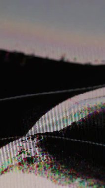 Dikey video. Arıza çatlağı. Kırık monitör. Hasarlı cam yüzeyin altına siyah sıvı dökülüyor. Arızalı yayın görüntüsünün homurtusu arkaplan.