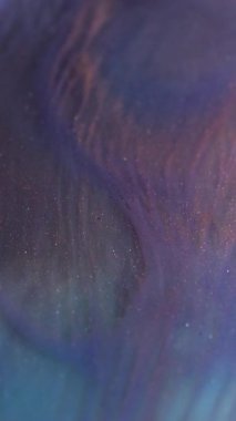 Dikey video. Parıltılı boya. Dalgalı akış. Yüzeyinde dalgalanmalar olan parıldayan mavi bir akıntı. Parlak sıvı sıvısı ve karıştırılmış boya parçacıkları çözünmüş etkisi.