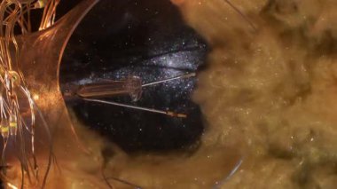 Dikey video. Parıltılı akıntı. Parlayan mürekkep. Siyah arka plan enkaz ampulünde altın dumanlı patlama. Yaratıcı soyut aydınlatılmış renk su yüzeyi.