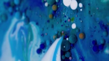 Dikey video. Renkli akış. Kabarcık boyası. Su yağı karışımı pigment damlası patlıyor. Mavi beyaz parçacıkları dolduran dalga koyu soyut arkaplan.