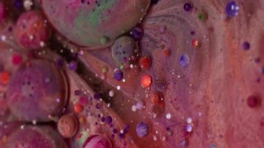 Dikey video. Mermer baloncuklar. Boya akışı. Fantezi gibi yuvarlak jel topları sanat yağı sıvısında fokurduyor. Pembe turuncu parçacıklar girdap şeklinde soyut arkaplan dökerler.