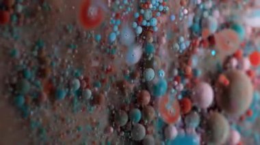 Dikey video. Köpüklü sis. Pigment dökülmüş. Küçük yuvarlak renk parçacıkları bulanık şeffaf sıvıda yüzen boyaları karıştırıyor. Petrol sanatı suyu soyut arkaplan.