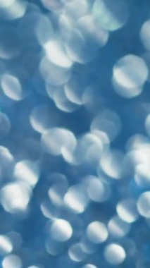 Dikey video. Bokeh parlıyor. Çok renkli ışıltı. Aydınlatılmış bulanık ışık noktalarıyla değişken dağılım. Havalı mistik parıltısıyla şenlikli bir arka plan..