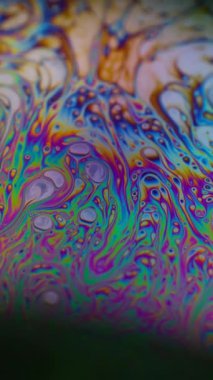 Dikey video. Soyut sanat. Sıvı sabun köpüğü. Odaklanmamış mor yeşil sıvı yağ eğrisi koyu siyah bulanık ışık arka planında akrilik kaygan.