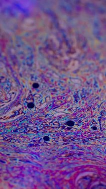 Dikey video. Soyut dağılım. Sıvı köpük. Odaklanmamış mor, yeşil yağ rengi eğrisi koyu siyah bulanık sanat arka planında akrilik kaygan.