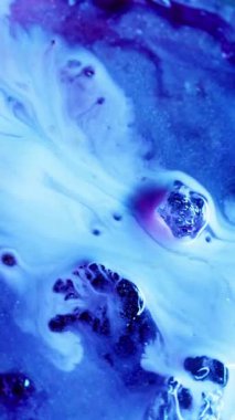 Dikey video. Mavi dökülmüş. Parlayan akıntı. İki püskürtülmüş sıvı boya renkli ışıl ışıl yüzeye dökülmüş. Suluboya parlak bulanık dokuya dökülüyor.