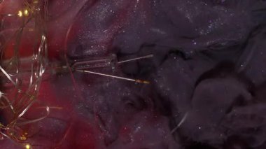 Dikey video. Işıldayan akış. Boya sisi. Genişleme parlak kırmızı parlak yüzey siyah dumanlı boyayla. Grunge kırık cam ampul soyut arkaplan.