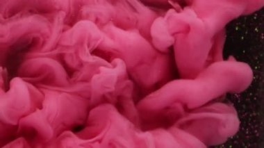 Mürekkep dumanı. Pembe duman. Parlak bulut tüm yüzeye yayılır. Suyun soyut arkaplanındaki karmaşık kıvrımlı parçacıklarla dekoratif olarak sislenmiş boya.