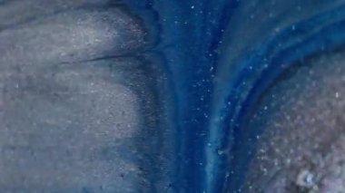 Işıldayan sıvı. Mürekkep arkaplanı. Mavi gri gri toz akıntısı siyah yüzeye yayılıyor. Soyut simli boya parçacıkları bulanıklığı.
