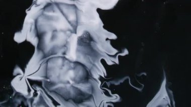 Mürekkep sıçraması. Beyaz leke. Geniş emaye akıntısı, karanlık ve düz olmayan bir yüzeye doğru karmaşık bir şekilde yayılır. Sanat sıvısı soyut arkaplanı aydınlatır.