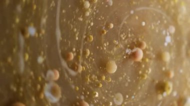 Dikey video. Girdabı boya. Yağ damlası akışı. Katmanlı mermer dairesel spin karışımı su soyut çözülmüş arka planda kahverengi bej mürekkep topları etrafında.