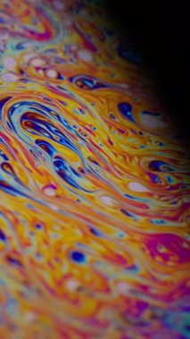 Dikey video. Gökkuşağı kıvılcımları. Mürekkep karışımı. Odaklanmamış mor yeşil sıvı yağ eğrisi koyu siyah bulanık ışık soyut sanat arka planında akrilik kaygan.