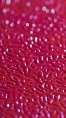 Dikey video. Bulanık doku. Yapay deri. Kırmızı dalgalı plastik yüzey rahatlaması ve değişen ışık. Dekoratif parlak arkaplan.